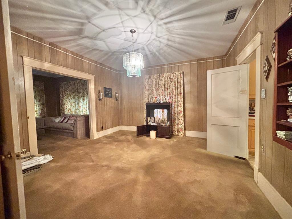619 Delaware Street Dallas, TX 75208 - Photo 3 of 13 an empty room with fireplace wooden floor and chandelier