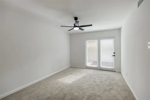 a view of an empty room and a chandelier fan