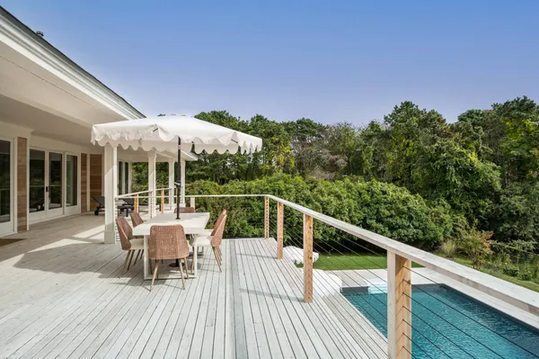 a balcony with wooden floor table and chairs