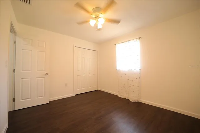 a view of a room with wooden floor and a ceiling fan