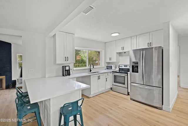 a kitchen with granite countertop a refrigerator a stove a sink dishwasher a dining table and chairs with wooden floor