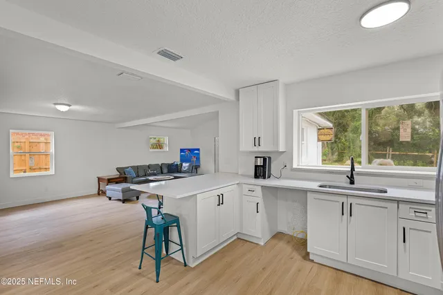a kitchen with a sink a window and chairs