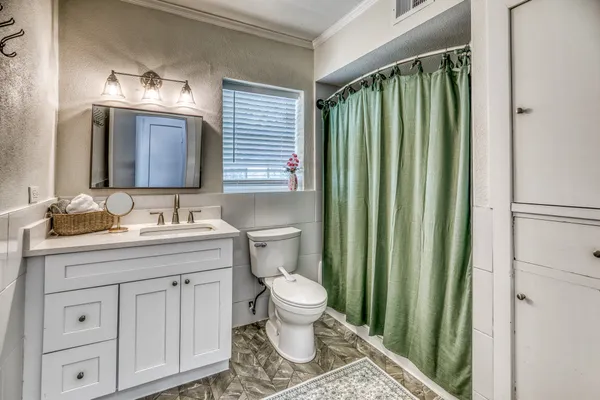 a bedroom with a bed a chandelier and a dresser