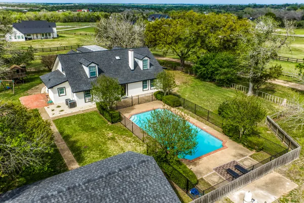 an aerial view of residential house with outdoor space and trees all around