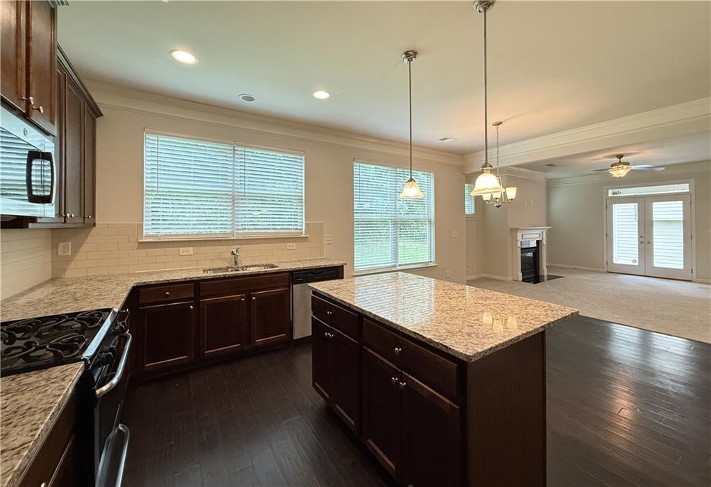 2467 Overlook Avenue Lithonia, GA 30058 - Photo 31 of 51 a kitchen with a stove kitchen island a sink dishwasher a stove and a wooden floor with potted plants