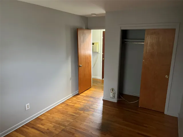 a view of an empty room with wooden floor and closet
