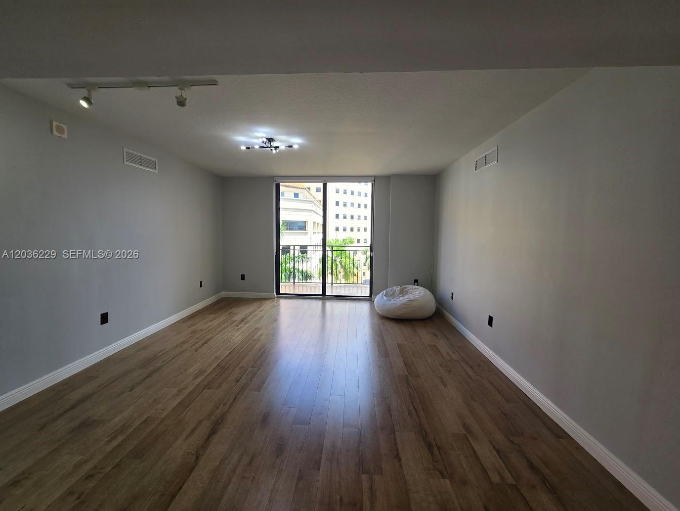 888 Douglas Road, Unit 605 Coral Gables, FL 33134 - Photo 7 of 21 an empty room with wooden floor and windows