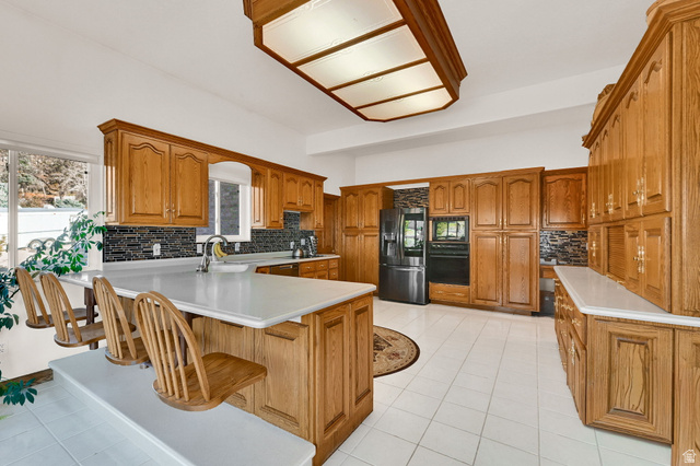 1085 Windsor Drive Provo, UT 84604 - Photo 18 of 83 Kitchen with brown cabinetry, a peninsula, black appliances, and backsplash