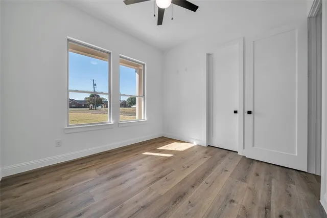 a view of an empty room with window and wooden floor