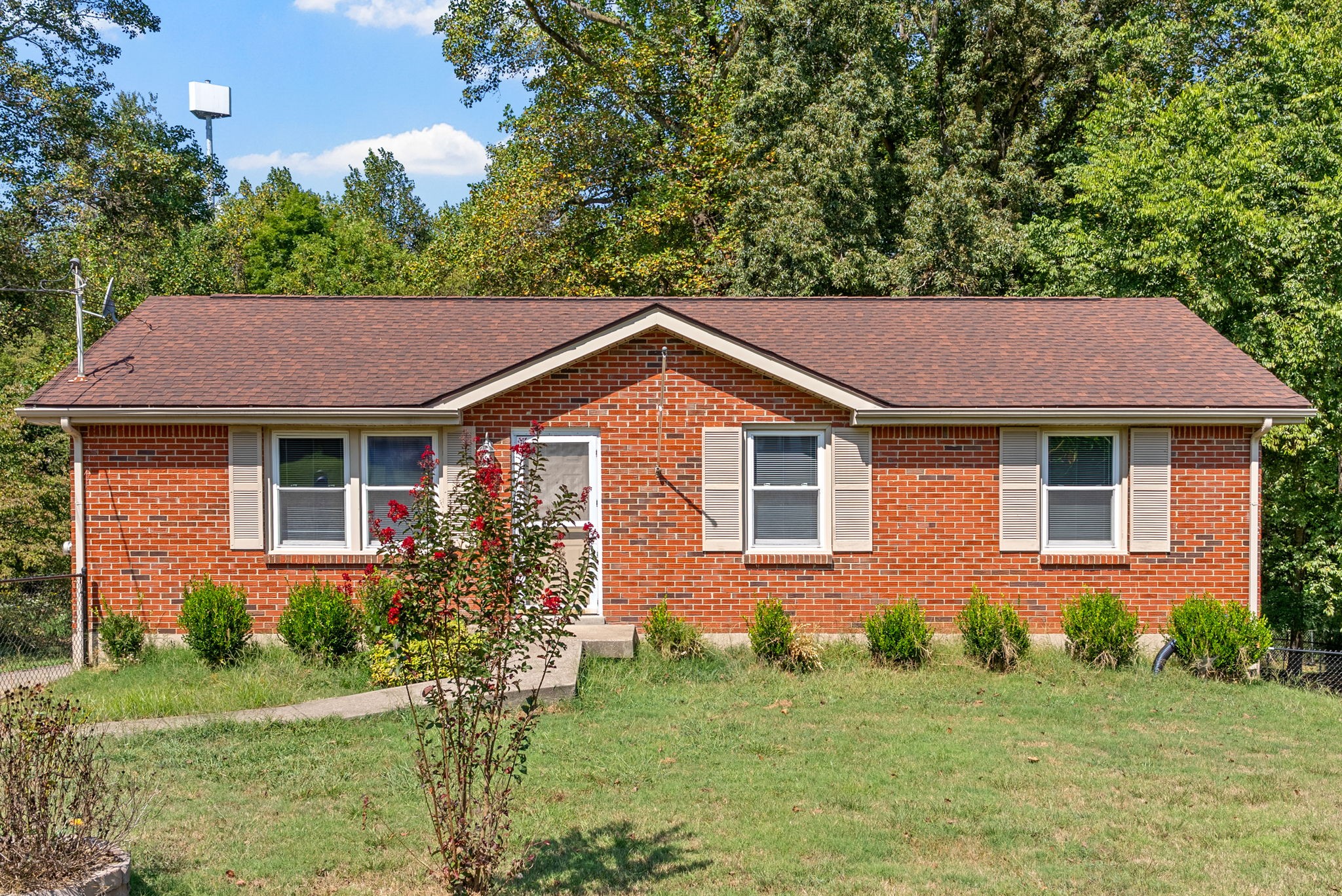 a view of a yard in front of a brick house with large windows