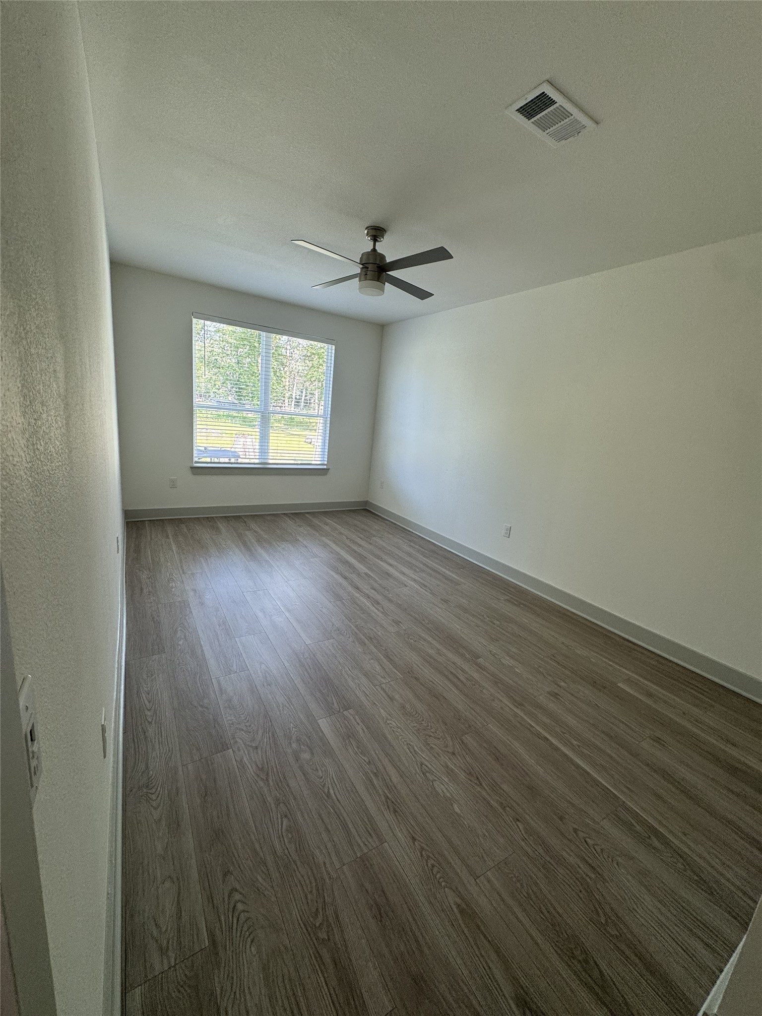 26244 Twin Oaks Road Splendora, TX 77372 - Photo 3 of 10 an empty room with wooden floor chandelier fan and windows