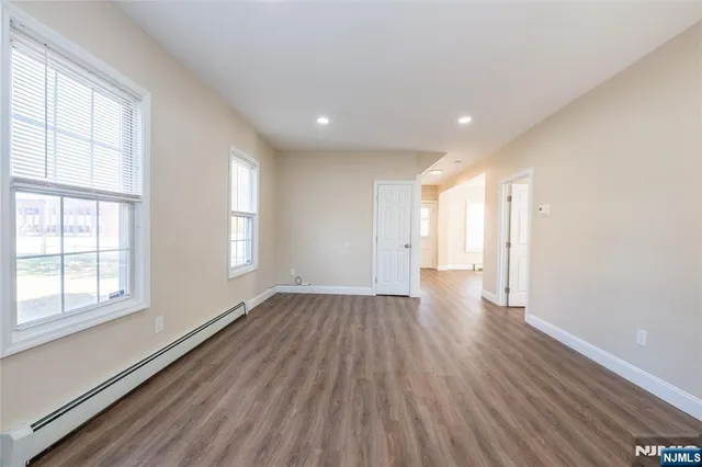 a view of an empty room with wooden floor and window