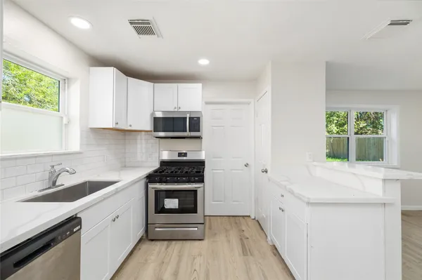 a kitchen with stainless steel appliances a stove sink microwave and cabinets