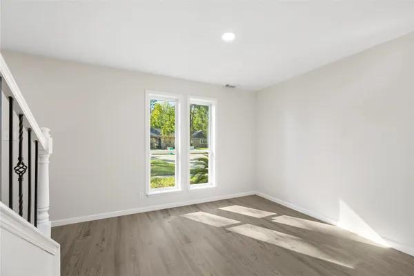 an empty room with wooden floor and windows
