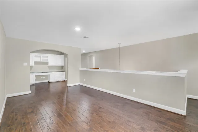 an empty room with wooden floor ceiling fan and windows