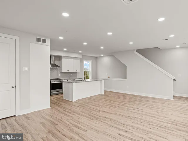 a large kitchen with a center island wooden floor and stainless steel appliances