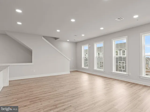a view of an empty room with wooden floor and windows