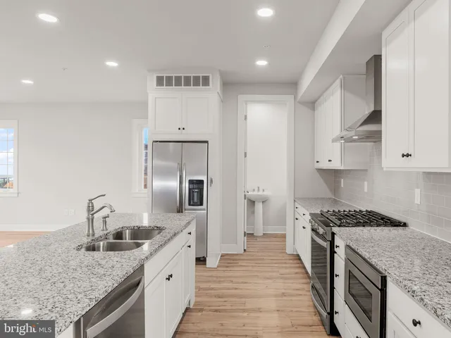 a kitchen with stainless steel appliances granite countertop a sink stove and refrigerator