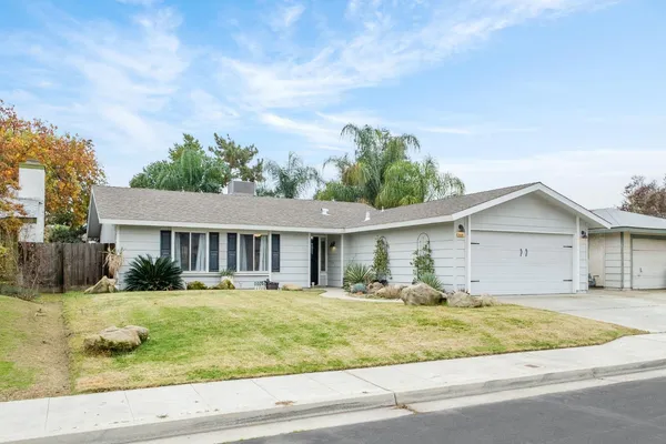 a kitchen with stainless steel appliances granite countertop a stove a sink dishwasher a refrigerator and white cabinets with wooden floor