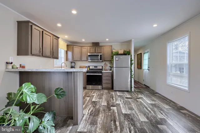 a kitchen with stainless steel appliances granite countertop a refrigerator sink a stove and a microwave oven