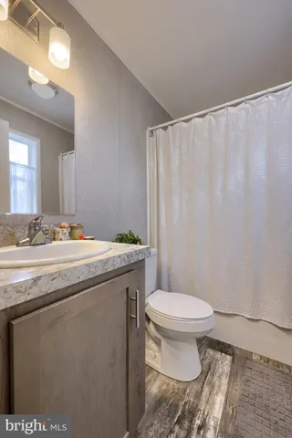 a bathroom with a granite countertop sink toilet and a mirror