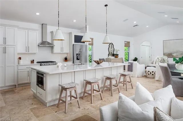 a kitchen with stainless steel appliances kitchen island granite countertop a stove a sink a refrigerator and white cabinets