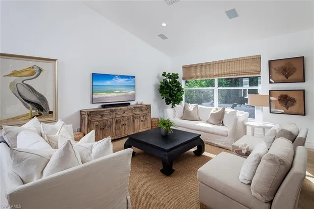 a living room with furniture a rug a flat screen tv and a large window