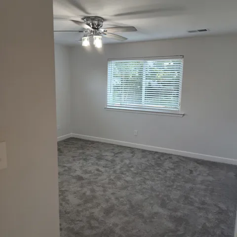 an empty room with windows and fan