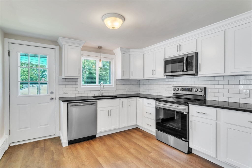800 Wilbraham Road Springfield, MA 01109 - Photo 6 of 21 a kitchen with stainless steel appliances granite countertop white cabinets a sink a stove a microwave and wooden floors