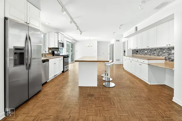 a kitchen with stainless steel appliances granite countertop a refrigerator a stove and a sink