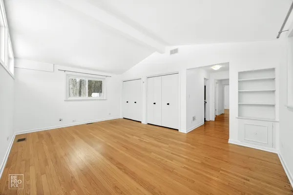 a view of an empty room with a window and wooden floor