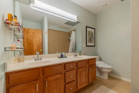 a bathroom with a double vanity sink toilet and mirror
