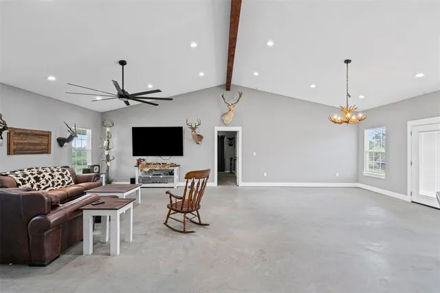 a living room with furniture a flat screen tv and a ceiling fan