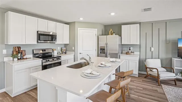 a kitchen with stainless steel appliances kitchen island granite countertop a stove a sink a dining table and chairs