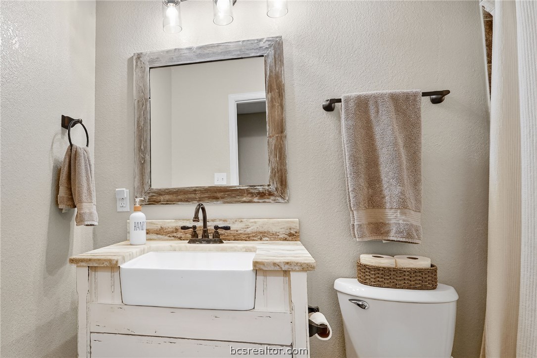 10054 Arnold Lane Bryan, TX 77845 - Photo 13 of 32 a bathroom with a sink vanity mirror and toilet