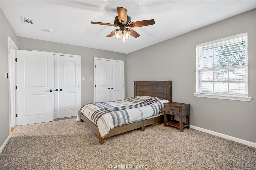 10054 Arnold Lane Bryan, TX 77845 - Photo 15 of 32 a spacious bedroom with a bed and a ceiling fan