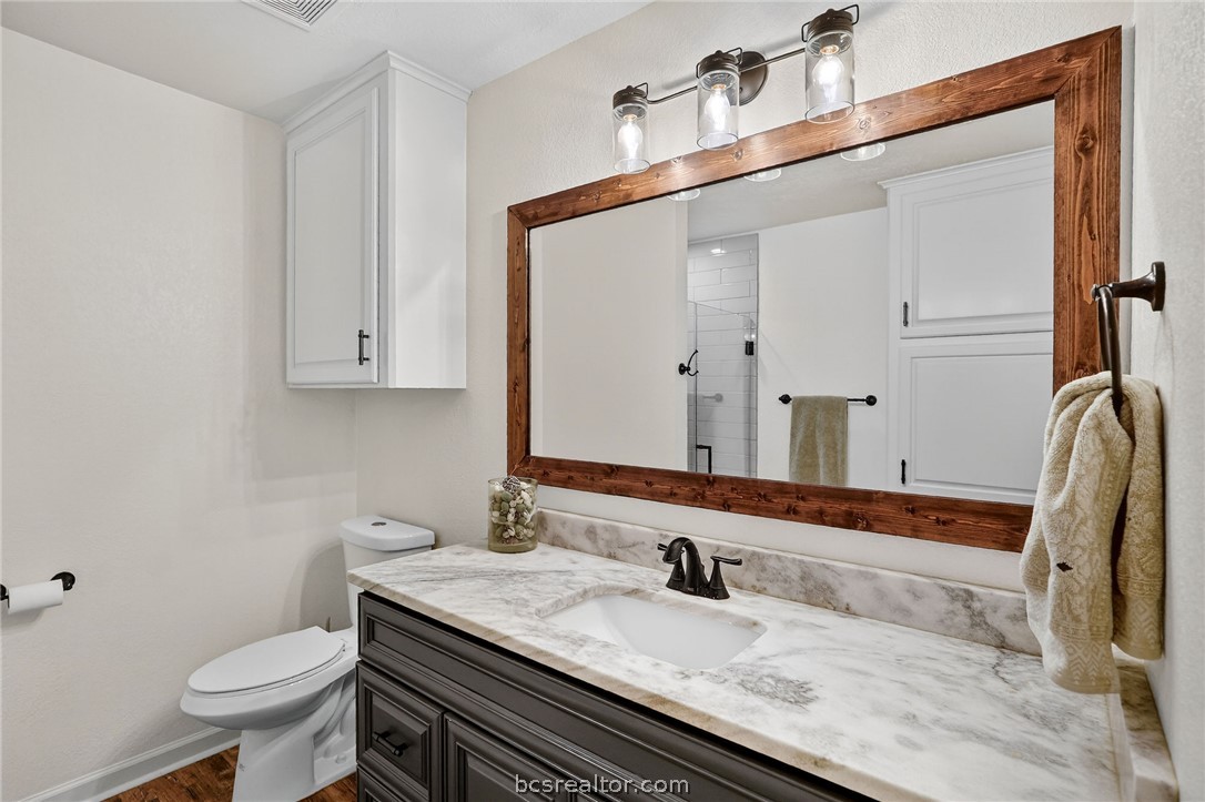 10054 Arnold Lane Bryan, TX 77845 - Photo 17 of 32 a bathroom with a granite countertop sink toilet and mirror