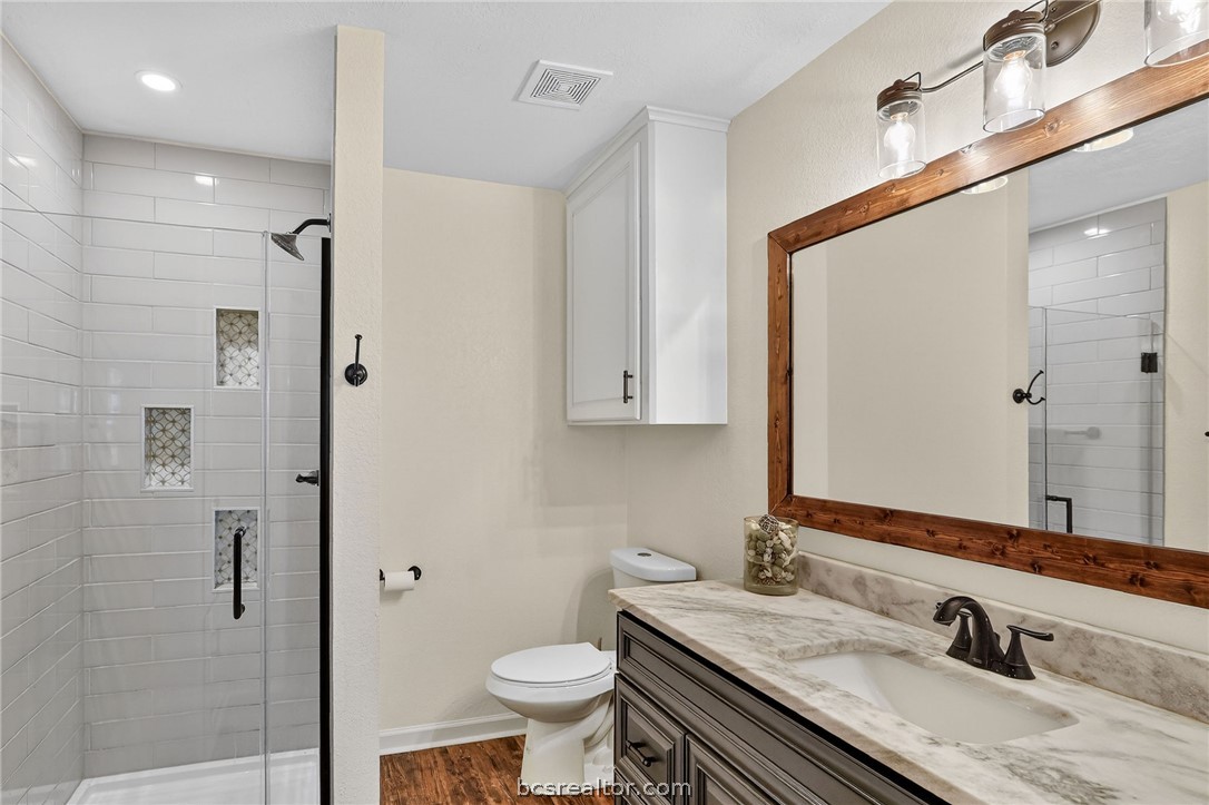 10054 Arnold Lane Bryan, TX 77845 - Photo 18 of 32 a bathroom with a granite countertop sink toilet and shower