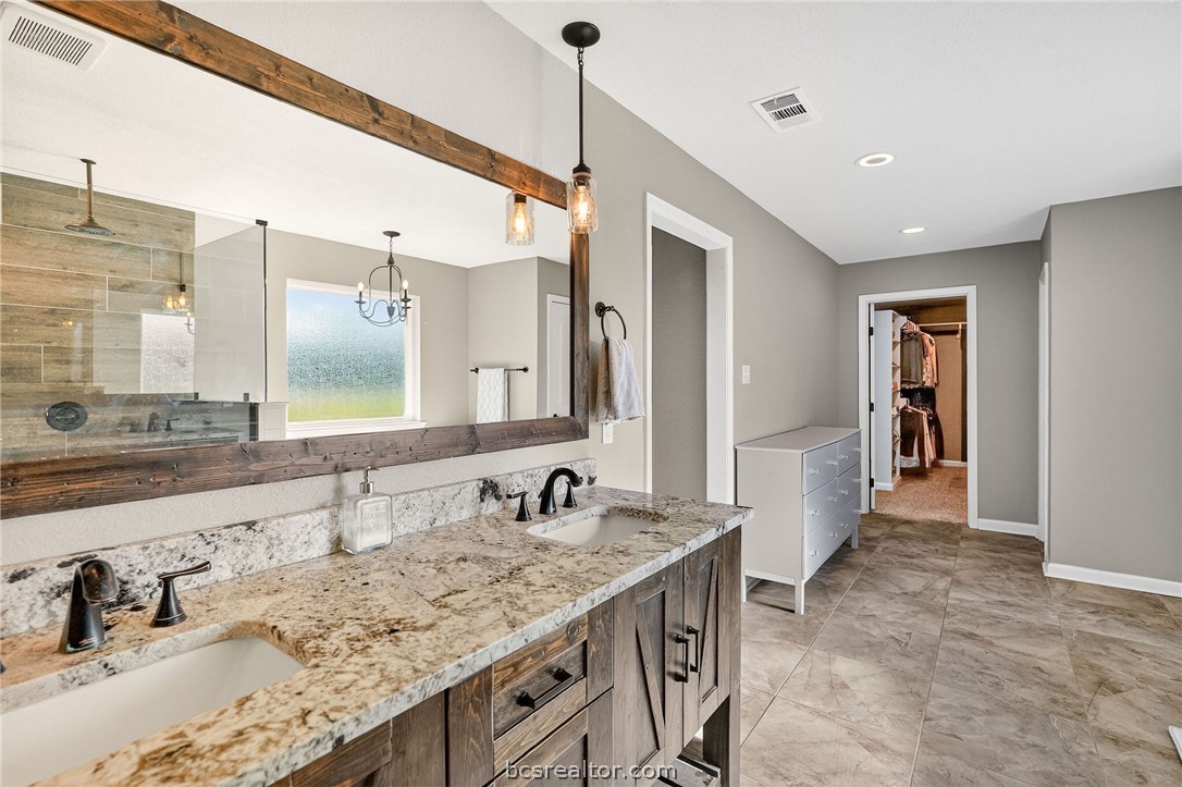 10054 Arnold Lane Bryan, TX 77845 - Photo 23 of 32 a bathroom with a granite countertop sink and a mirror