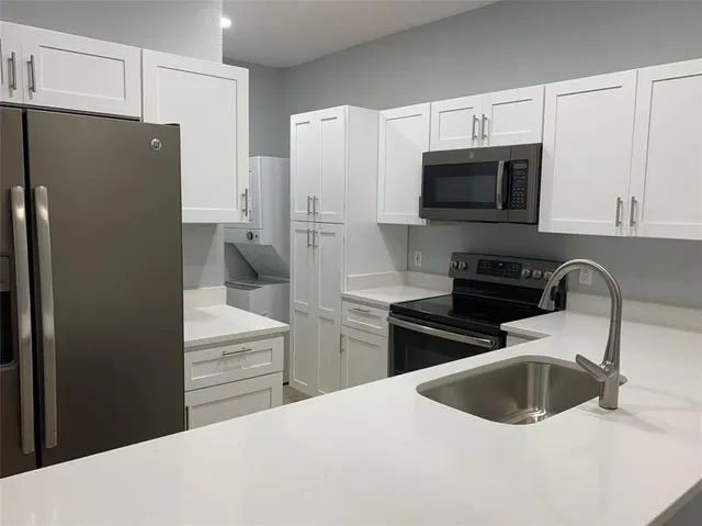 a kitchen with stainless steel appliances a refrigerator sink and white cabinets