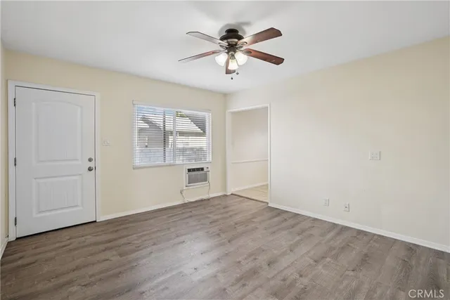 an empty room with wooden floor chandelier fan and windows