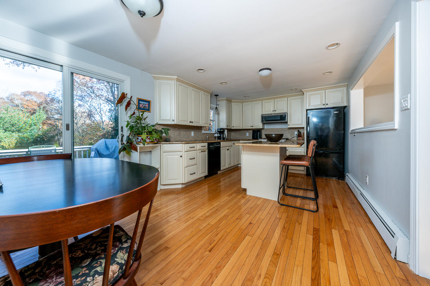 4 Oregon Road Mashpee, MA 02649 - Photo 18 of 31 a kitchen with stainless steel appliances granite countertop a refrigerator a sink dishwasher a stove and a dining table with wooden floor