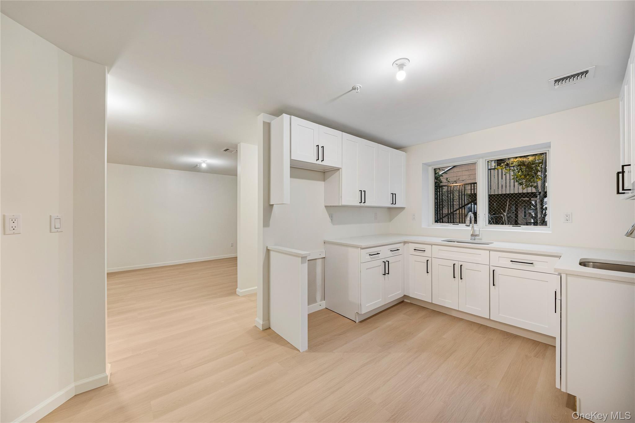 12 Buckman Place, Unit 101 Monsey, NY 10952 - Photo 40 of 50 Kitchen with white cabinetry, light wood-style flooring, and light stone countertops