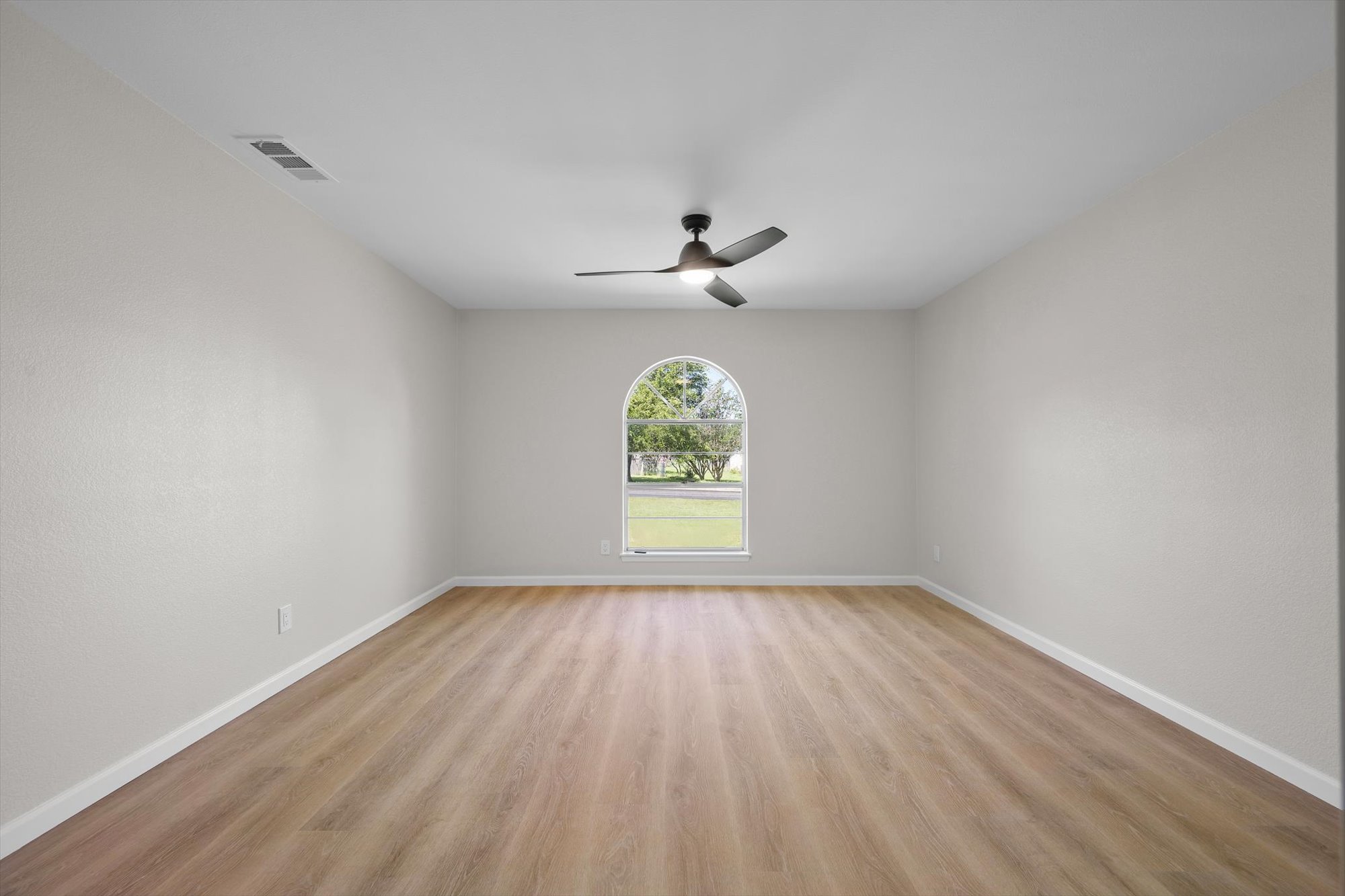 109 Woodland Road Georgetown, TX 78628 - Photo 33 of 40 A well-lit room showcases durable laminate flooring, an arched window, and a modern ceiling fan.