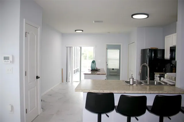a dining hall with stainless steel appliances granite countertop a sink and chairs