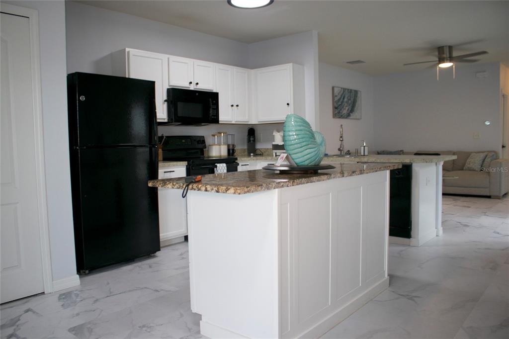 12107 Barnsley Reserve Place Gibsonton, FL 33534 - Photo 7 of 26 a kitchen with a sink a microwave a refrigerator and cabinets