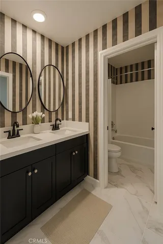 a bathroom with a double vanity sink a toilet and shower