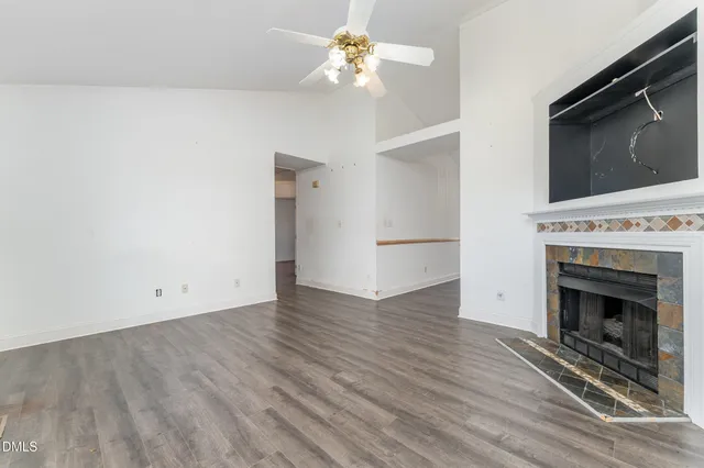 a view of an empty room with chandelier fan and fire place