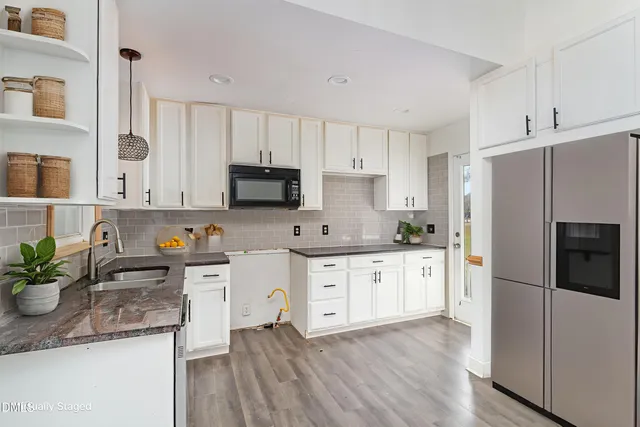 a kitchen with stainless steel appliances white cabinets a sink a stove a refrigerator and microwave