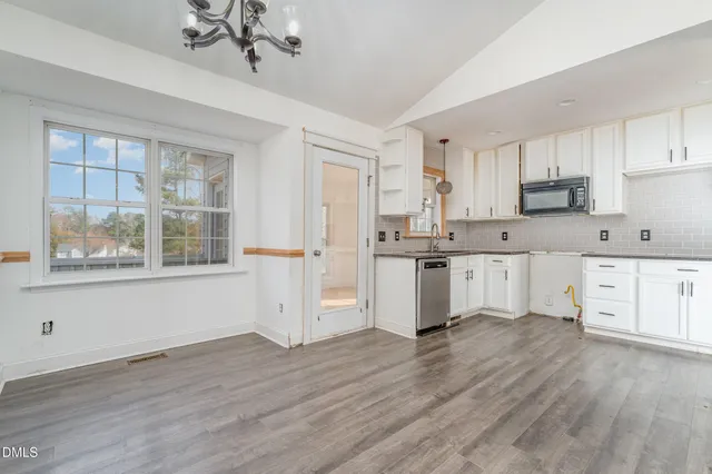 a kitchen with stainless steel appliances kitchen island wooden floors and white cabinets